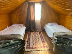 two beds in a wooden room with a window at Orbis Bude in Samshvilde