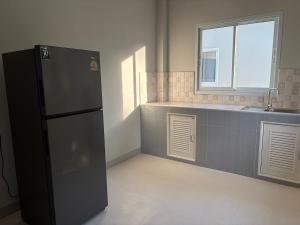 eine Küche mit einem schwarzen Kühlschrank und einem Fenster in der Unterkunft Mini House in Koh Samui 