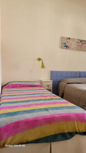 a bed with a colorful striped comforter in a room at Locanda FarOrientale in Santa Lucia