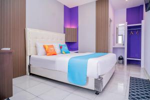 a bedroom with a large white bed with colorful pillows at SANS Vibes Violeta Inn Jambi in Jambi
