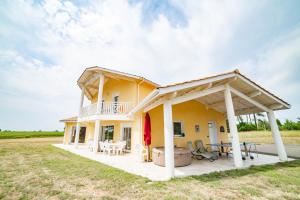 a large yellow house with a deck and patio at L'Horizon des Chênes - grand jardin, bbq & table de ping pong in Hagetmau
