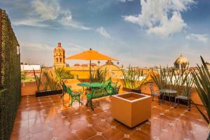 une terrasse avec une table, des chaises et un parasol dans l'établissement Hotel Templo Mayor, à Mexico