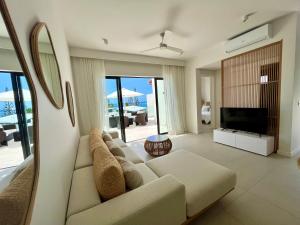 a living room with a couch and a television at Exclusive beachfront penthouse in Belle Mare