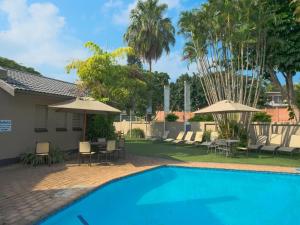 a swimming pool with chairs and umbrellas next to a house at Lakeview Cabanas - Unit 11 in St Lucia +49 photos