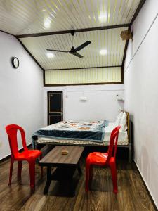 a room with a bed and two red chairs at Lake breeze homestay in Shendi