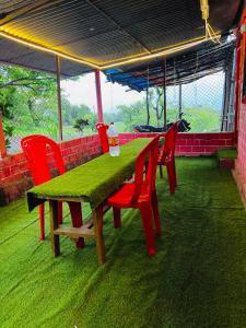 a table with red chairs and a green table and chairs at Lake breeze homestay in Shendi