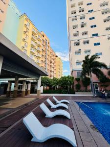 a couple of white chairs sitting next to a swimming pool at JFam Suites, C3-9D Studio, Up To 4 Pax in Biñan