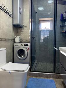 a bathroom with a shower and a washing machine at Sabi Guest House in Bokonbayevo