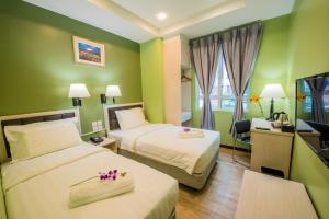 Cette chambre comprend deux lits et une télévision. dans l'établissement inHotel Inanam, à Kota Kinabalu