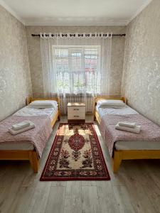 a bedroom with two beds and a rug at Sabi Guest House in Bokonbayevo