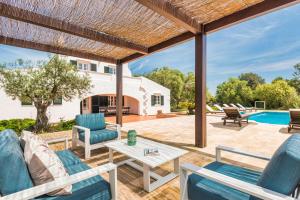 a patio with chairs and a table and a pool at Villa Mig Coster - Refugio rural en finca privada in Sant Lluis