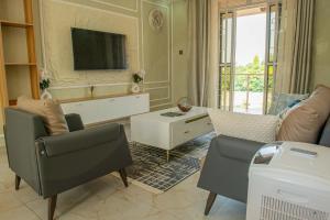 a living room with two chairs and a tv at E- Residence in Gulu