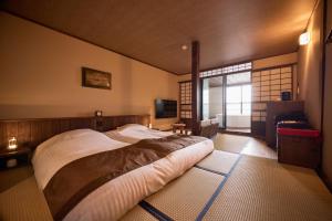 a bedroom with a large bed and a window at いっぺ The Sake Ryokan in Kyonan