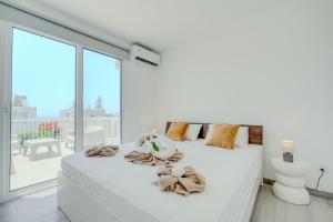 a white bedroom with a white bed and a large window at Sandy Beach Complex in Perivolia