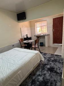 a bedroom with a bed and a table and chairs at ELISAM Cabin 2 in Kitwe