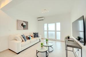 a white living room with a couch and a table at Sandy Beach Complex in Perivolia