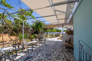eine Terrasse mit Tischen, Stühlen und Bäumen in der Unterkunft Studios Nina in Amoopi