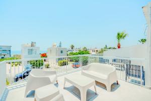 a balcony with white chairs and a table at Sandy Beach Complex in Perivolia