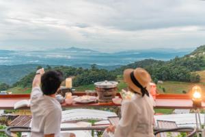 two people sitting at a table looking out at the mountains at MonPhuView MonJam ม่อนภูวิว ม่อนแจ่ม in Mon Jam