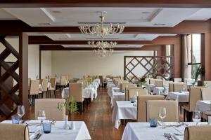 a restaurant with white tables and chairs and a chandelier at Atlantica Grand Mediterraneo Resort - Adults Only in Kompítsion