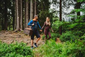 a man and a woman walking in the woods at Chalets Jasná Collection Záhradky in Belá