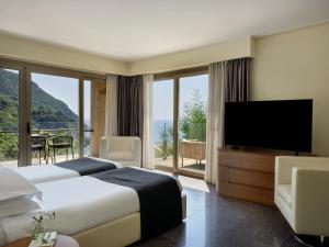 a hotel room with a bed and a flat screen tv at Atlantica Grand Mediterraneo Resort - Adults Only in Kompítsion