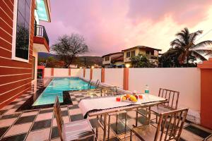 eine Terrasse mit Tisch und Stühlen neben einem Swimmingpool in der Unterkunft II EMPYREAN STAYS II SU CASA VILLA II 4BHK II AC II PRIVATE POOL Il in Lonavla