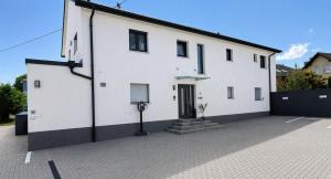 a white building with a driveway in front of it at Heimbi-Home No 3 I 4-6 Personen I EuropaPark I Family I Garten I Parkplatz I E-Ladestation in Kappel-Grafenhausen