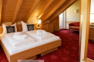 a bedroom with a large bed with white sheets at Sporthotel Auhof in Kappl