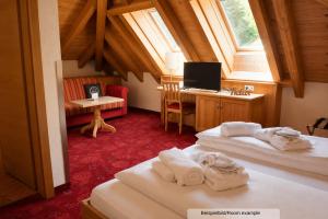 a room with two beds and a desk with a computer at Sporthotel Auhof in Kappl