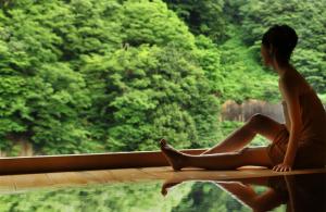 a woman sitting on a ledge next to a body of water at Enraku in Kurobe +99 photos