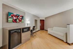 a living room with a white couch and a tv at Red Roof Inn & Suites Newport - Middletown, RI in Middletown