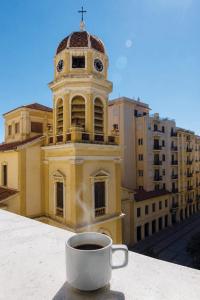 a cup of coffee sitting on a ledge with a clock tower at Elisabeth Boutique Hotel in Thessaloniki