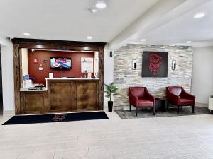 a restaurant with two red chairs and a bar at Red Roof Inn & Suites Newport - Middletown, RI in Middletown