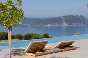 a row of lounge chairs sitting next to a swimming pool at Villa Kairos in Foiníki