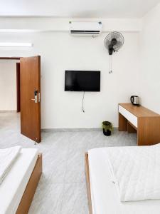 a white room with a bed and a tv on a wall at Minh Anh Hotel Nghệ An in Vinh