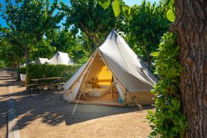 a tent is set up in the shade of trees at Kampaoh Blanes in Blanes
