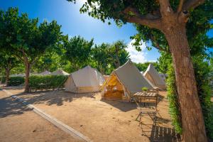 a group of tents with chairs and a tree at Kampaoh Blanes in Blanes +35 photos