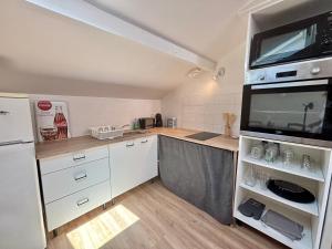 a small kitchen with white cabinets and a microwave at Charmant Duplex climatisé, Centre de Cahors in Cahors +2 photos