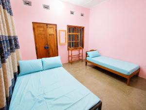 a room with two beds and a door at Yarl Retreat - Jaffna Town - Non-AC in Jaffna +2 photos