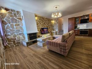 a living room with a couch and a stone fireplace at PELION HORIZON houses in Agios Ioannis Pelio
