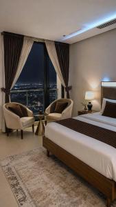 a bedroom with a bed and two chairs and a large window at The Vista 1BR by Winchester in Mall of Islamabad F-7 Margalla & City Views in Islamabad