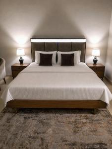 a bedroom with a large white bed with two lamps at The Vista 1BR by Winchester in Mall of Islamabad F-7 Margalla & City Views in Islamabad