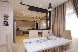 a kitchen and dining room with a white table and chairs at 3 bedrooms Entebbe Lake-House with Pool,Private Beach, Kids Park and AC in Kagolomolo