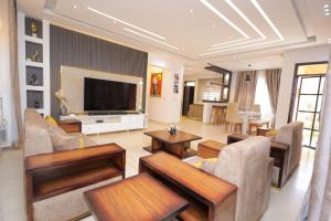 a living room with a couch and a television at 3 bedrooms Entebbe Lake-House with Pool,Private Beach, Kids Park and AC in Kagolomolo