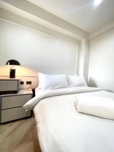 a white bedroom with a bed and a nightstand at RESET at DMK Hotel in Don Muang Airport