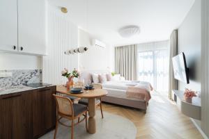 a bedroom with a bed and a table and a kitchen at Laguna Beskidów Resort - Studio Sultanit in Zarzecze