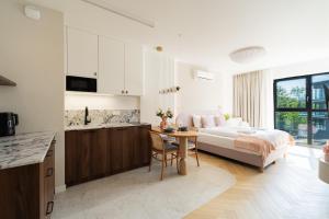 a bedroom with a bed and a table and a kitchen at Laguna Beskidów Resort - Studio Sultanit in Zarzecze