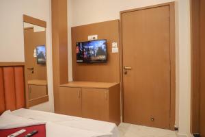 ein Zimmer mit einer Tür und einem Fernseher an der Wand in der Unterkunft Hotel Pramila in Mumbai