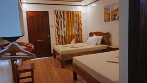 a small room with two beds and a table at Rabang Inn in San Vicente